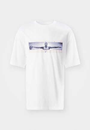 T-shirt de algodão branco com um design central impresso de um jogador com os braços estendidos, texto a dizer "ASAS", e detalhes gráficos subtis.