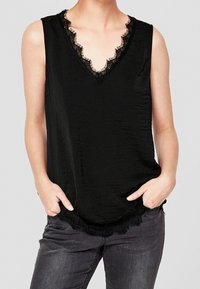 Černý bezrukávový top s výstřihem do V ozdobený krajkovým lemem, s jemnou texturou a zakřiveným lemem. Spárován s tmavými džíny.