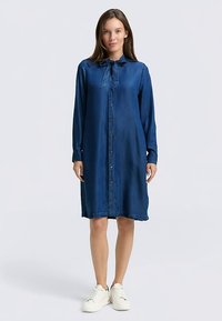 Denim overhemdjurk in donkerblauw, met lange mouwen, knoopsluiting aan de voorkant en een gestrikte kraag. Gladde textuur en een losse pasvorm.