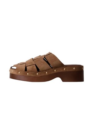 Sandale mule en daim marron à bout ouvert avec larges brides, semelle plateforme basse et détails de clous dorés le long du bord de la semelle.