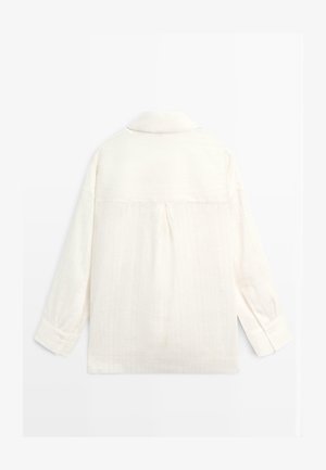 Long-sleeve cream-colored shirt with a collar, buttoned cuffs, and a central pleat on the back, displayed flat on a white background.