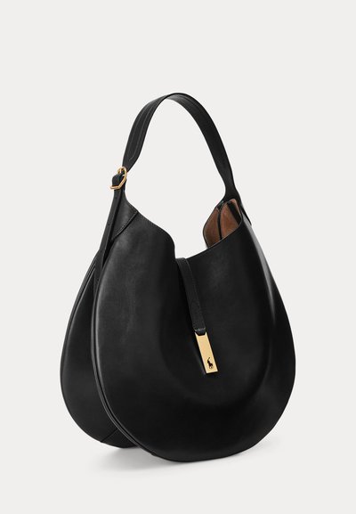 Sac à épaule en cuir noir en forme de croissant avec une bandoulière simple, une boucle dorée et une petite étiquette rectangulaire dorée avec logo sur le devant.