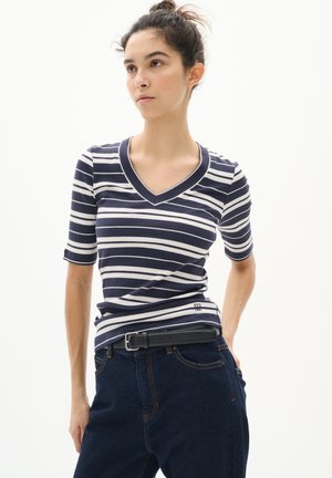 Marineblå och vit randig kortärmad V-ringad topp, ribbad textur, bärs med mörkblå jeans och ett svart bälte, med logotypdetalj.