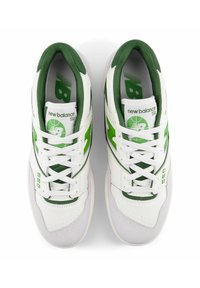 White and green New Balance 550 sneakers feature a smooth leather upper, padded collar, perforated toe box, and logo accents.