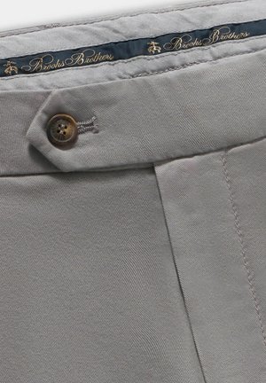 Grijze katoenen stofbroek met een enkele bruine knoopsluiting en een blauwe tailleband met "Brooks Brothers" in goud gegraveerd.
