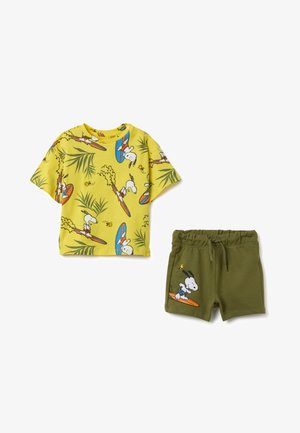 Camiseta amarilla de manga corta con un estampado de tabla de surf y palmera, combinada con pantalones cortos verde oliva que presentan un gráfico de Snoopy y una cinturilla elástica.