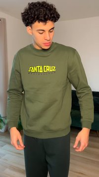 Olive green sweatshirt with a round neckline and ribbed cuffs, featuring a vibrant yellow and gray "SANTA CRUZ SKATEBOARDS" logo.