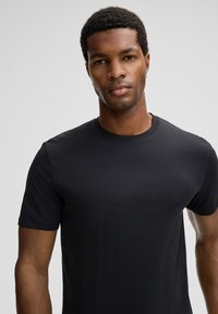 Zwarte korte mouwen t-shirt van gladde katoenen stof, met een ronde hals en een getailleerde pasvorm. Eenvoudig en onopgesmukt ontwerp.