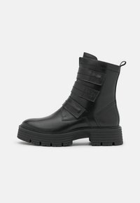 Bottines en cuir noir avec trois sangles ajustables, un bout arrondi et une semelle en caoutchouc robuste avec un profil texturé.