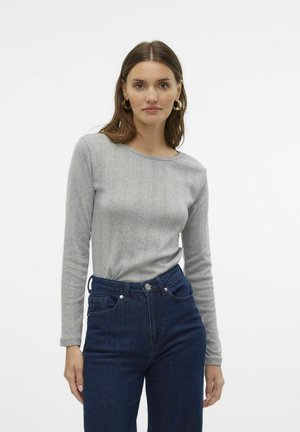Grå langermet topp med rund hals og vertikalt ribbestrikket tekstur, sammen med mørkeblå høytlivsjeans.
