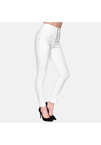 Jean skinny taille haute blanc au toucher lisse, avec une fermeture éclair et trois boutons, ajusté jusqu'à la cheville.