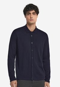 Marinblå långärmad skjorta med knappar och krage i mjukt material. Har en framknäppning med matchande knappar.