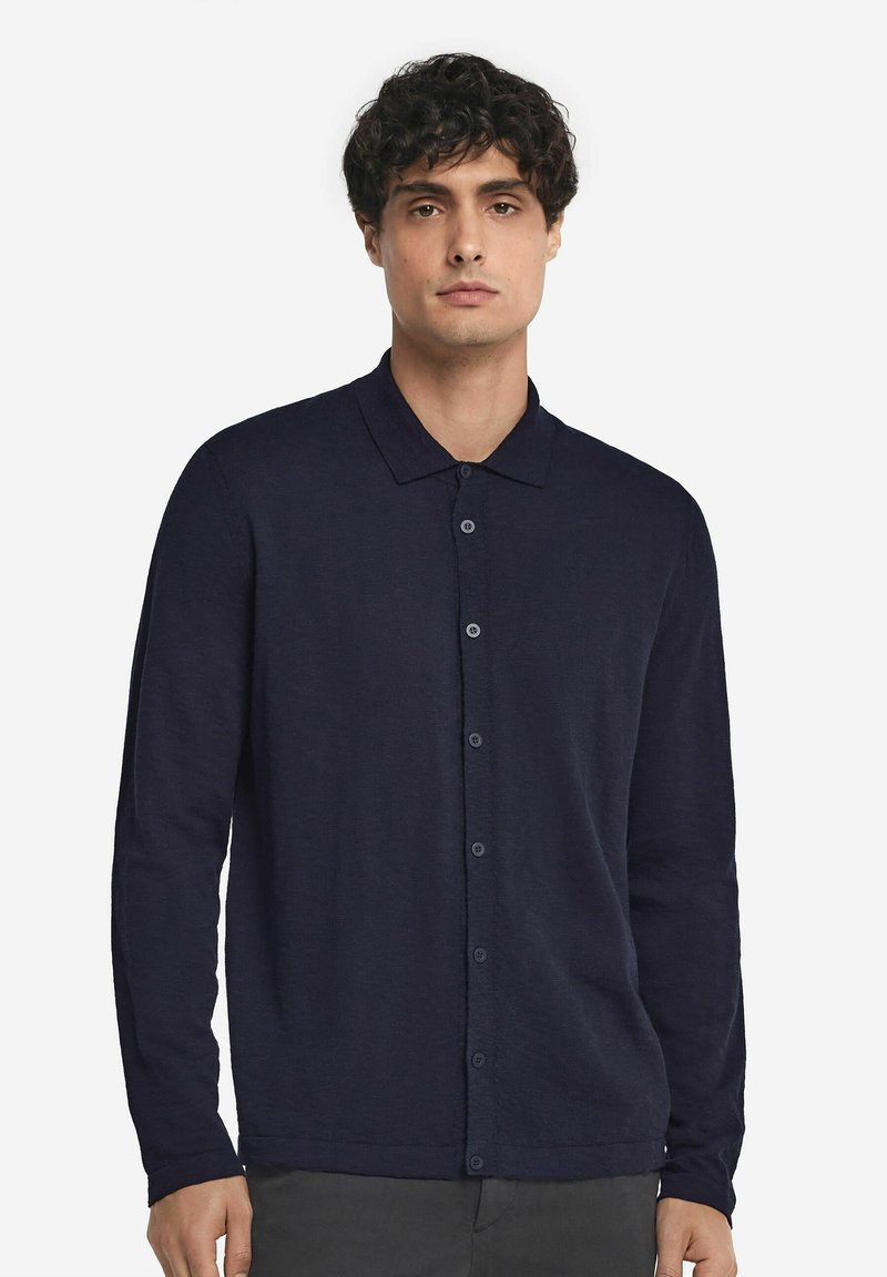 Marinblå långärmad skjorta med knappar och krage i mjukt material. Har en framknäppning med matchande knappar.