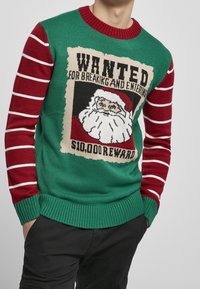 Grön stickad tröja med röda randiga ärmar, med ett "Wanted"-affischmotiv med jultomten. Materialet är en akrylblandning; ribbade manschetter.