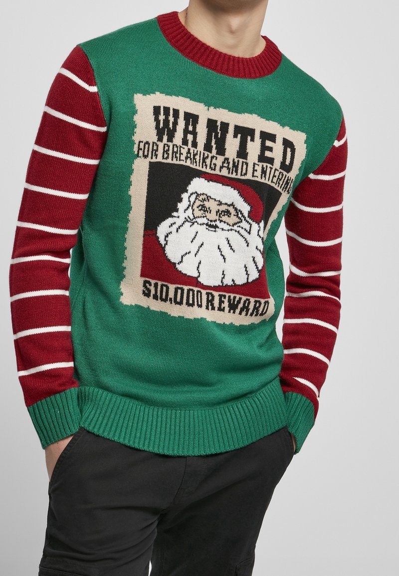 Grön stickad tröja med röda randiga ärmar, med ett "Wanted"-affischmotiv med jultomten. Materialet är en akrylblandning; ribbade manschetter.
