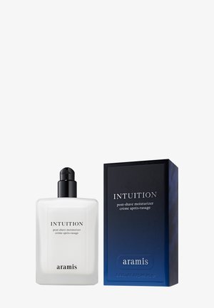 Fuktighetskrem til etter barbering i en klar flaske med svart pumpe, ved siden av en blå og svart rektangulær eske med hvit tekst.