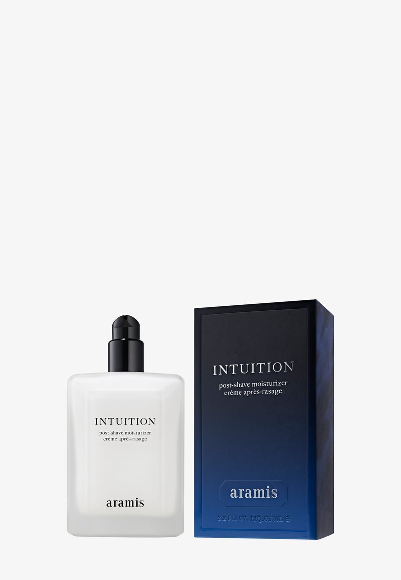 Aftershave-Feuchtigkeitscreme in einer klaren Flasche mit einem schwarzen Pumpverschluss, neben einer blau-schwarzen rechteckigen Box mit weißem Text.