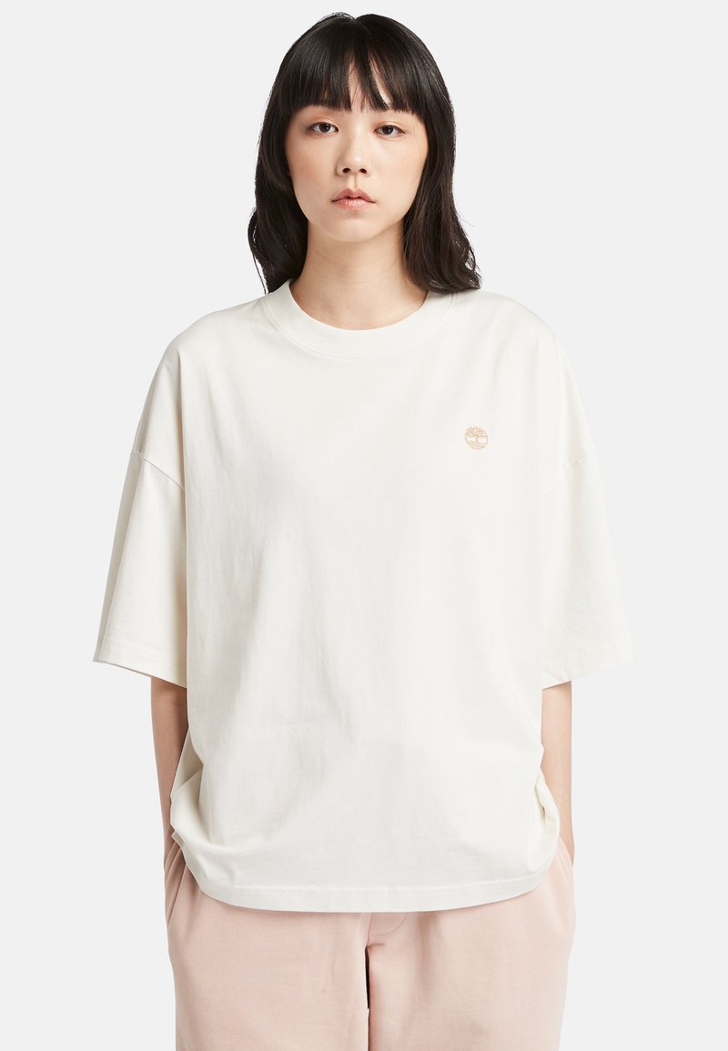 Vit oversized bomull t-shirt med rund halsringning och korta ärmar. Har en liten broderad logotyp ovanför vänster sida.