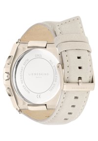 Roestvrijstalen horloge met een zilveren kast, witte leren band en zichtbare stiksels. Heeft een ronde, doorzichtige achterkant met branding.