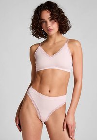 Lichtroze geribd stoffen lingerieset met een bralette afgewerkt met kant en verstelbare bandjes, en een bijpassende hoge taille string.