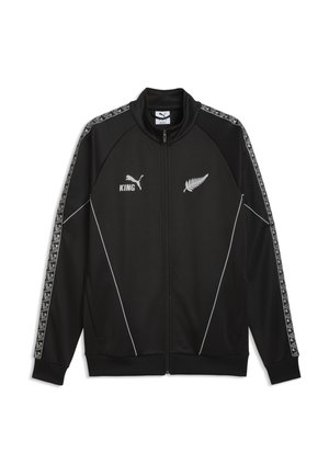 Schwarze Sportjacke mit Reißverschluss, weißen Farn- und Puma-Logos, dem Schriftzug "KING" und gemusterten Streifen an den Ärmeln.