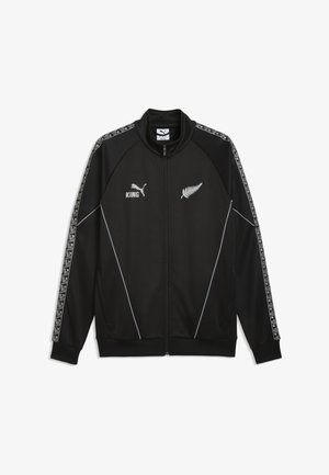 Schwarze Sportjacke mit Reißverschluss, weißen Farn- und Puma-Logos, dem Schriftzug "KING" und gemusterten Streifen an den Ärmeln.