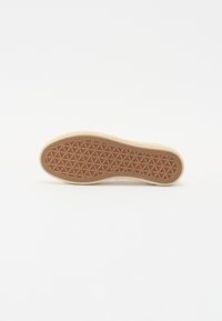 Rubber sole with a tan color and geometric pattern, featuring a textured surface for grip, with a light-colored upper edge.
