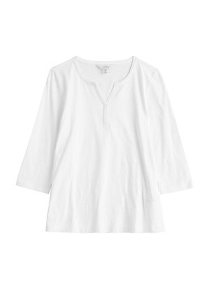 Haut long à manches blanches en coton avec un décolleté en V, présentant une patte central et des fentes sur les côtés à l'ourlet pour un confort de mouvement.