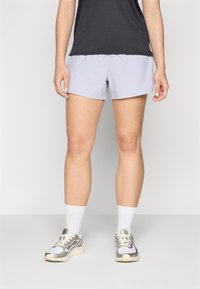 Lyse lilla treningsshorts laget av lett materiale, kombinert med en svart topp og grå joggesko, med hvite ankelsokker.