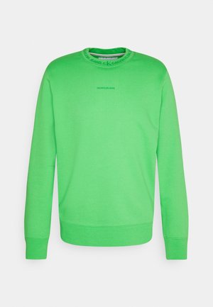 Bright green long-sleeve sweatshirt with "Calvin Klein Jeans" text on chest and branded round neckline.