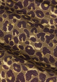 Leopard print fabric featuring a textured surface with brown and gold tones, showcasing irregular dark brown spots against a tan background.