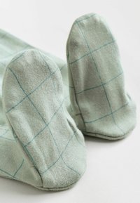 Chaussettes en coton vert avec un motif en grille de teinte plus claire. Elles ont des pointes arrondies et une texture douce, conçues pour le confort.