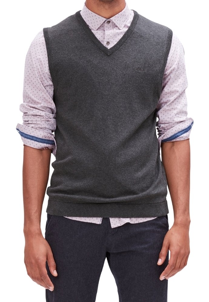 Maglione smanicato grigio a maglia con scollatura a V, indossato sopra una camicia botton down a pois rosa chiaro. Vestibilità slim con orlo a costine.