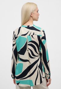 Langärmlige Bluse aus leichtem Stoff mit abstraktem Muster in Türkis, Marineblau und Creme, mit plissiertem Rücken und geknöpften Manschetten.