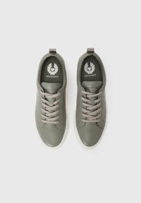 Sapatilhas verdes de couro com atacadores cinzentos, biqueira redonda e solas de borracha brancas. Apresentam o logo da BELSTAFF nas palmilhas.