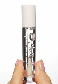Fiale di vetro trasparente con testo argentato, dotata di un tappo bianco. Contiene un liquido con bolle; tenuta in una mano.