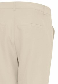 Pantaloni beige con una texture liscia, design a gamba dritta e due tasche posteriori con aperture piatte.