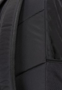 Schwarzer Nylon-Rucksack mit strukturiertem Stoff, gepolsterten Abschnitten und einer Netzseitentasche. Saubere Linien und minimalistisches Design.