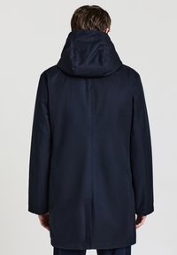 Cappotto blu navy con cappuccio, caratterizzato da una texture liscia, maniche lunghe e dettaglio di apertura posteriore, progettato per garantire calore e copertura.