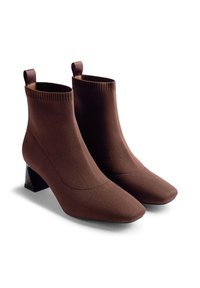 Botine tricotate maro, cu vârf ascuțit, toc pătrat și guler cu nervuri; prezintă o textură netedă și o construcție din material.