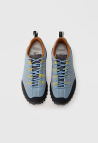 Μπλε σουέντ αθλητικά παπούτσια με μαύρες λαστιχένιες σόλες, κίτρινες και πορτοκαλί λεπτομέρειες, και επένδυση εσωτερικά σε ταμπά χρώμα με μαξιλαράκι. Διαθέτουν δετό σχεδιασμό με κορδόνια.