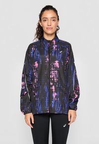 Veste noire légère avec un motif abstrait violet et rose, zip complet, col haut et poignets élastiques. Présente des accents réfléchissants.