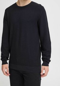 Pulover tricotat texturat de culoare neagră, cu mâneci lungi, guler rotund și manșete striate. Un model orizontal subtil pe întreaga țesătură.