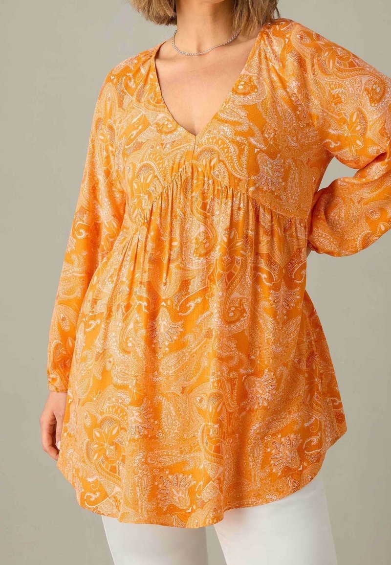 Blusa de color naranja con estampado paisley, de manga larga, escote en V profundo y detalle fruncido en la cintura, fabricada en tejido ligero.