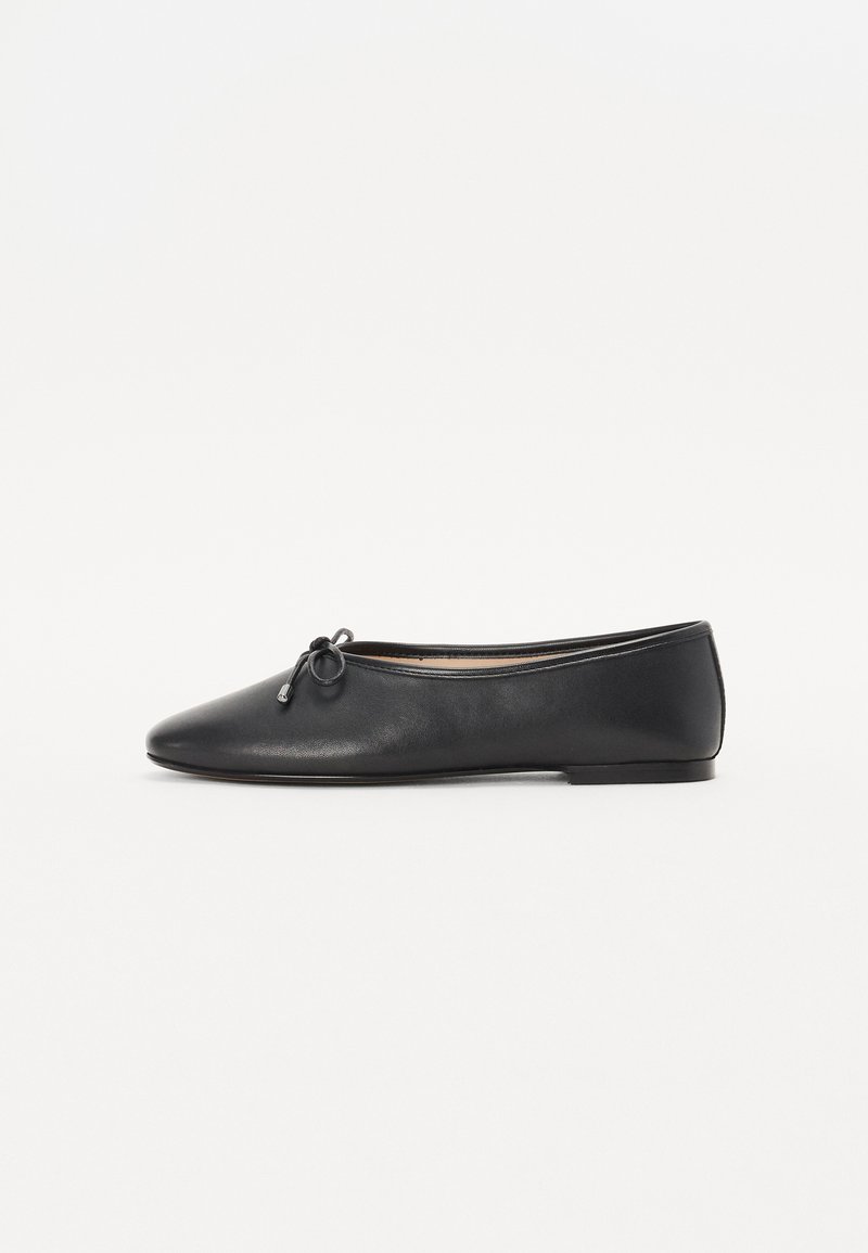 Ballerine en cuir noir avec un bout rond et un détail de nœud décoratif. Le design présente une texture lisse et un talon bas et plat.