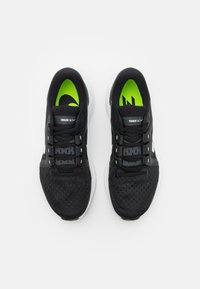 Black running shoes with green accents, mesh upper, padded collar, and white midsole. Features a structured lacing system for support.