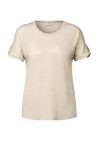 Ljust beige kortärmad T-shirt, rund halsringning, mjuk textur, uppvikt ärmar, diskret lyster, med ett varumärkesetikett inuti kragen.