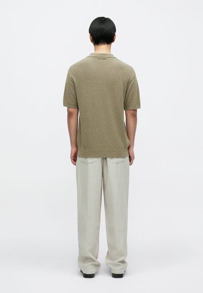 Κοντομάνικο πικέ πουκάμισο πόλο σε ελαιόχρωμο, συνδυασμένο με ελαφριά λινά παντελόνια, με άνετη εφαρμογή και ευθεία γραμμή στο πόδι.