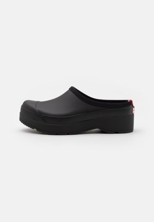 Black rubber clogs with a raised heel, rounded toe, and textured sole. Features a soft, padded rim and a red accent at the back.