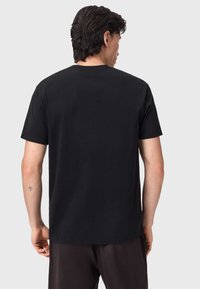 Μαύρο βαμβακερό t-shirt με κοντά μανίκια, στρογγυλή λαιμόκοψη και λεία, ομοιόμορφη υφή. Μινιμαλιστικός σχεδιασμός χωρίς εκτυπώσεις ή διακοσμητικά στοιχεία.